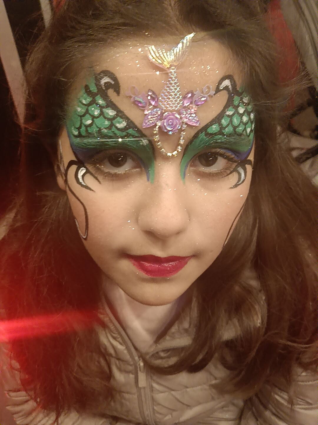 Maquillage sirène avec écailles vertes et bijoux strass irisés sur le visage d une enfant